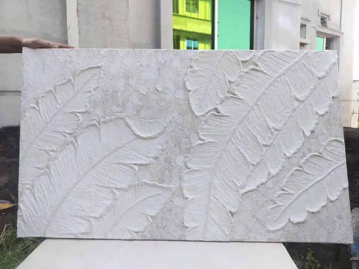 All-white relief artwork of large banana leaves on a crackled plaster background